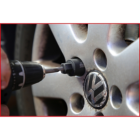 Nahaufnahme einer Person, die mit einem Akkuschrauber eine Radmutter an einem VW-Rad löst.